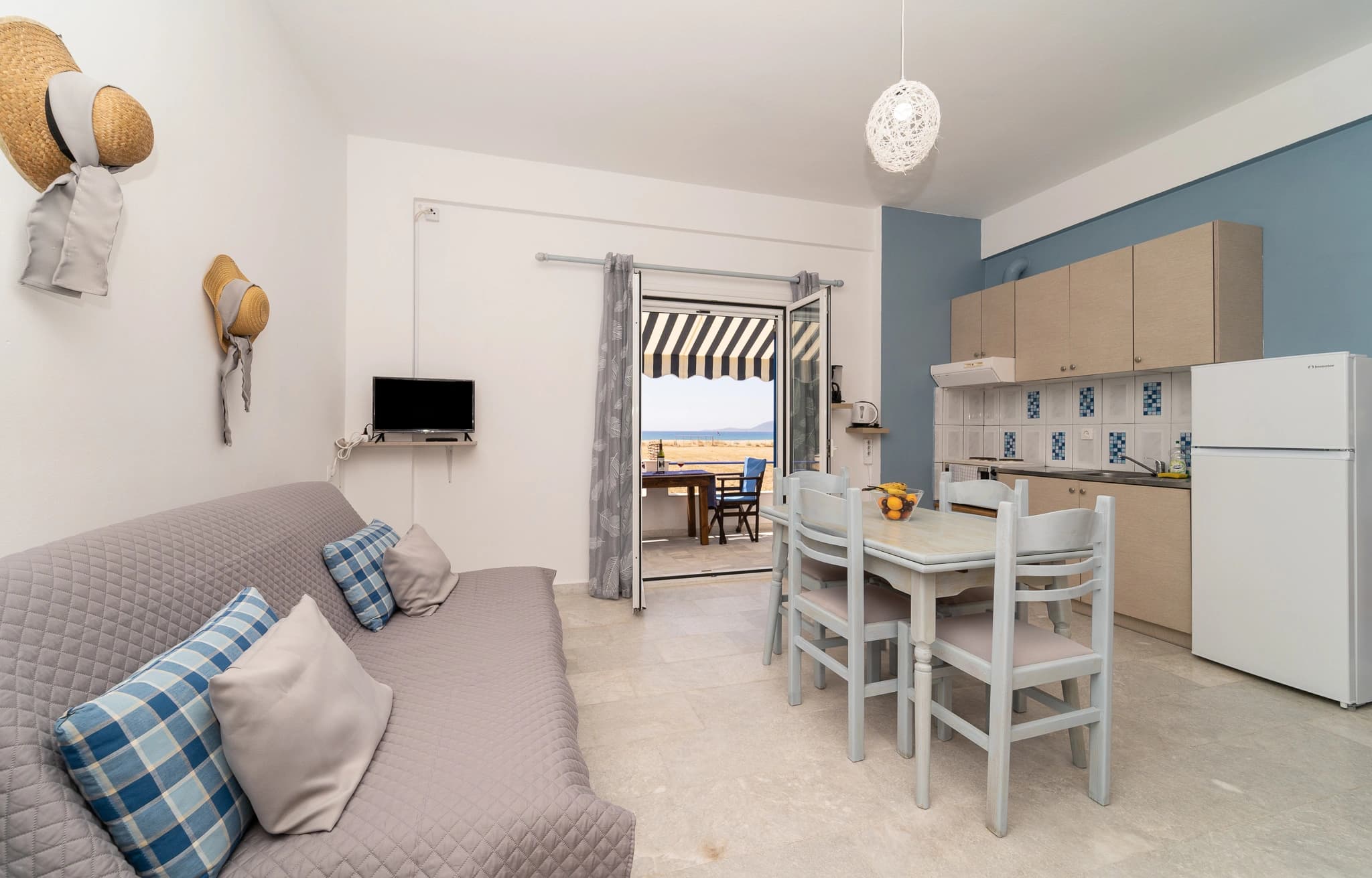 Open-plan interior of a Blue Houses apartment with kitchen, dining table and sofa bed
