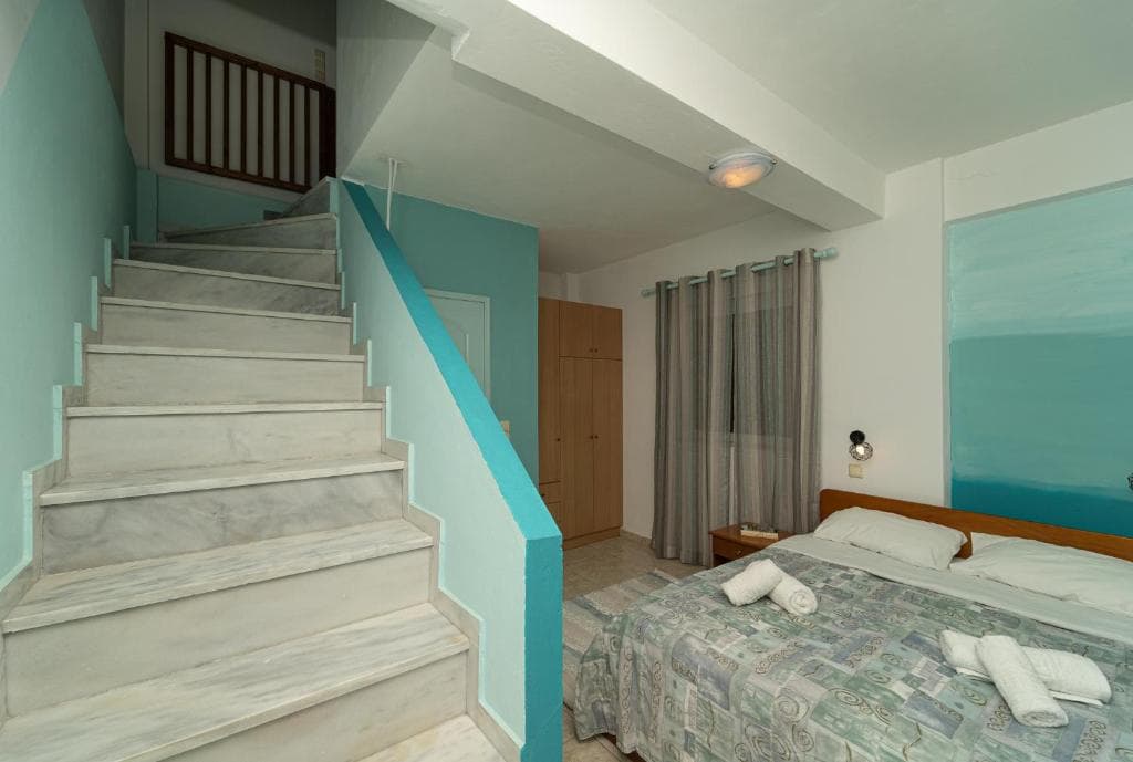 The lower floor of a maisonette, with a double bed and marble stairs leading up